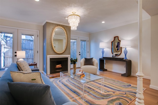 living room featuring crown molding, wood-type flooring, french doors, and a chandelier