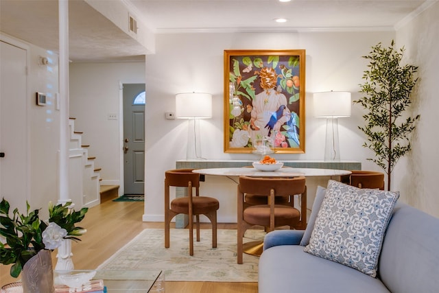 living area with ornamental molding and light hardwood / wood-style flooring