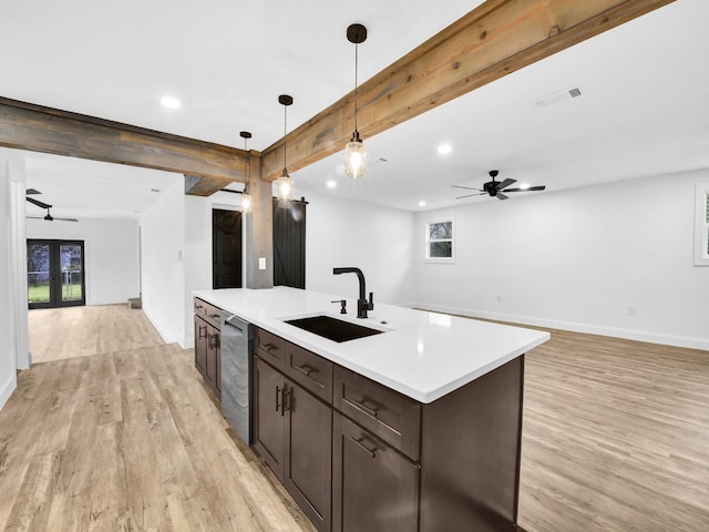 kitchen featuring decorative light fixtures, sink, stainless steel dishwasher, light hardwood / wood-style floors, and beam ceiling