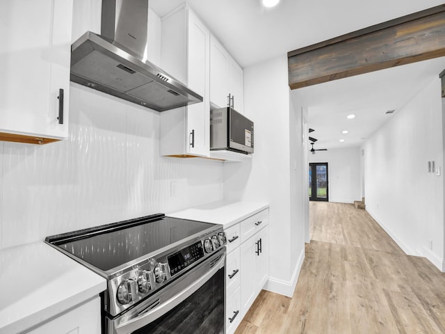 kitchen with white cabinets, stainless steel electric stove, wall chimney exhaust hood, and ceiling fan