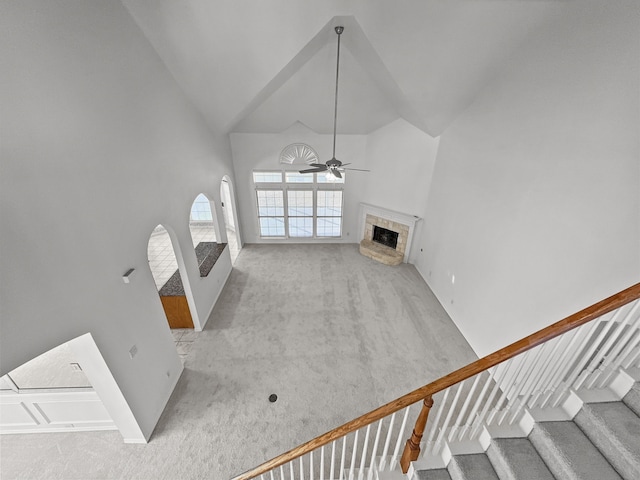 unfurnished living room with high vaulted ceiling, light colored carpet, and ceiling fan