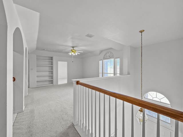 corridor with built in shelves and light colored carpet