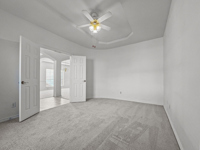 carpeted spare room featuring a tray ceiling and ceiling fan