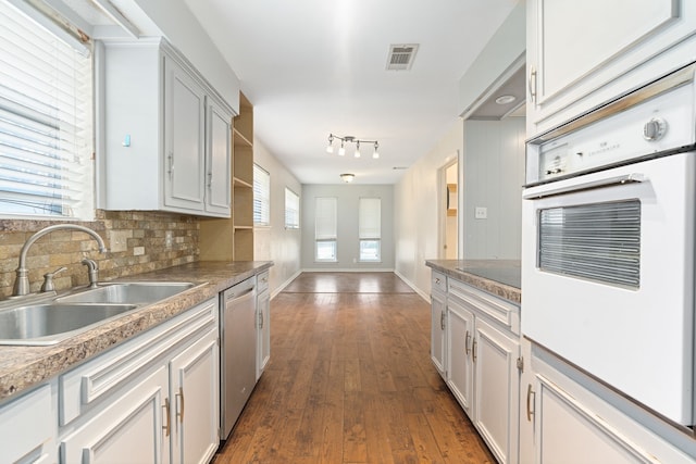 kitchen featuring stainless steel dishwasher, oven, sink, and white cabinets