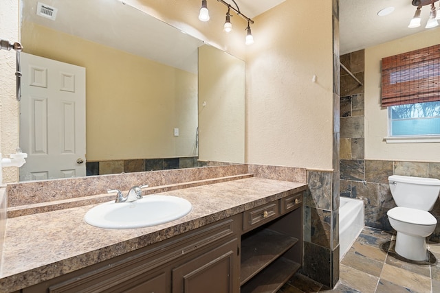 full bathroom with tile walls, vanity, bathtub / shower combination, and toilet