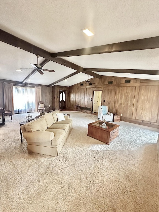 carpeted living room featuring vaulted ceiling with beams, a textured ceiling, a ceiling fan, and wooden walls