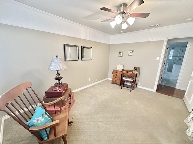 living area with carpet floors, a ceiling fan, visible vents, baseboards, and ornamental molding