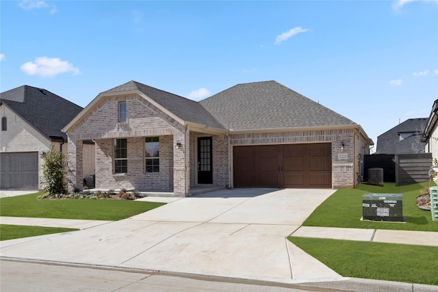 7221 Ladybug, Little Elm, TX 76227 - french country home featuring a garage, brick siding, concrete driveway, a front yard, and central air condition unit