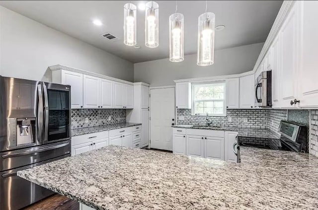 kitchen featuring decorative light fixtures, sink, white cabinets, backsplash, and stainless steel appliances