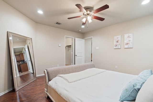 bedroom with ceiling fan, dark hardwood / wood-style floors, and a walk in closet