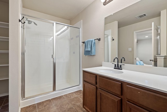 bathroom featuring a shower with door and vanity