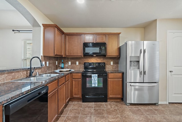 kitchen with sink, backsplash, dark stone counters, and black appliances