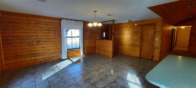 unfurnished dining area featuring a chandelier and wooden walls