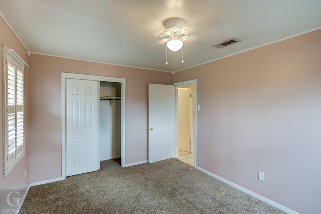 unfurnished bedroom with light carpet, ornamental molding, and a closet