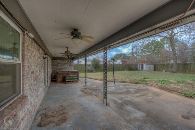 view of patio featuring a hot tub, ceiling fan, and a storage unit