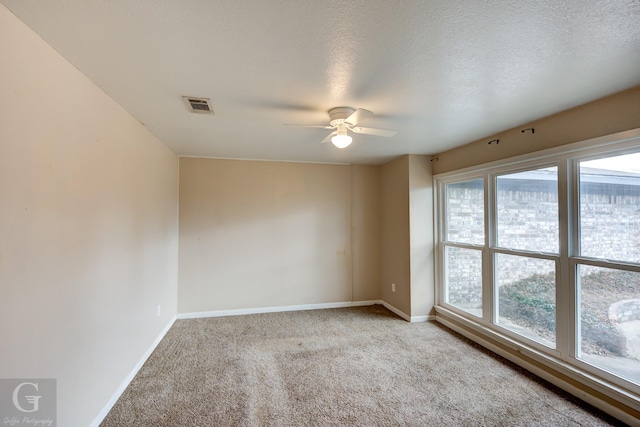 carpeted empty room featuring ceiling fan and a textured ceiling