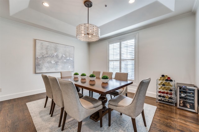 dining space featuring a raised ceiling, ornamental molding, dark wood-type flooring, and a chandelier