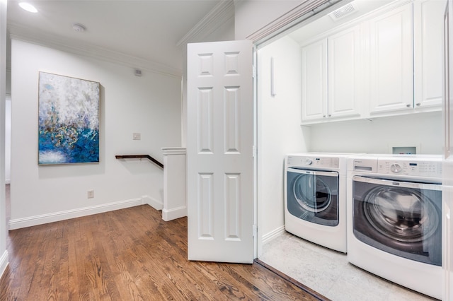 laundry room featuring crown molding, dark wood-type flooring, cabinets, and washing machine and clothes dryer