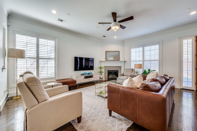 living room with crown molding, ceiling fan, a fireplace, and dark wood-type flooring