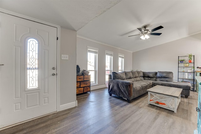 living room featuring ceiling fan, lofted ceiling, wood-type flooring, and ornamental molding