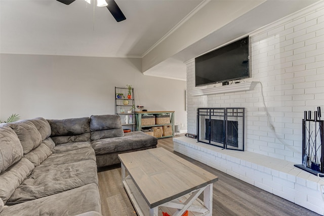 living room with ceiling fan, ornamental molding, wood-type flooring, and a brick fireplace