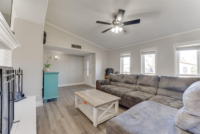 living room featuring vaulted ceiling, plenty of natural light, ornamental molding, and light wood-type flooring