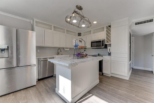 kitchen featuring pendant lighting, sink, white cabinetry, stainless steel appliances, and a center island