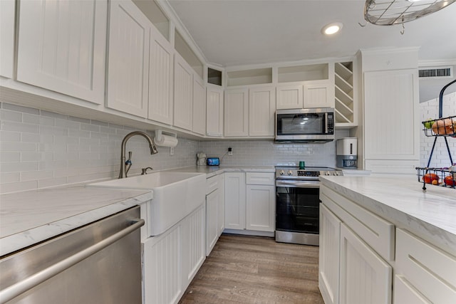 kitchen featuring appliances with stainless steel finishes, sink, white cabinets, decorative backsplash, and light hardwood / wood-style flooring