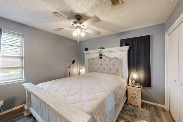 bedroom with ceiling fan, hardwood / wood-style flooring, a closet, and a textured ceiling