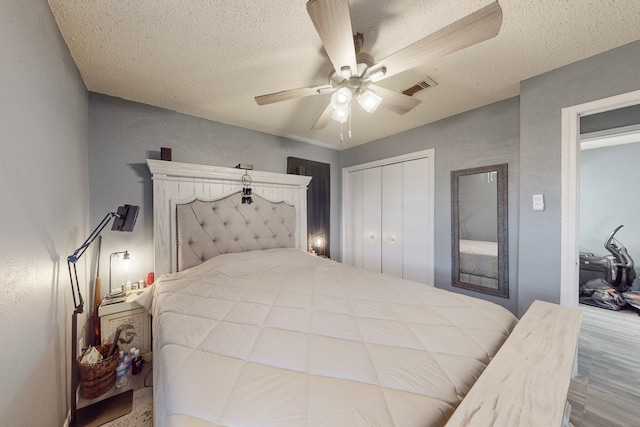 bedroom with ceiling fan, hardwood / wood-style floors, a closet, and a textured ceiling