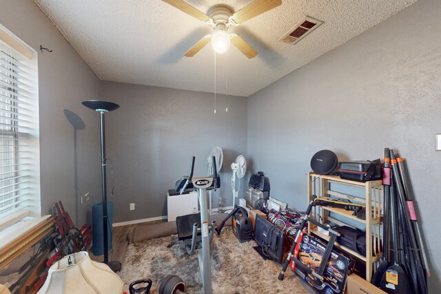 workout room with ceiling fan, plenty of natural light, and a textured ceiling