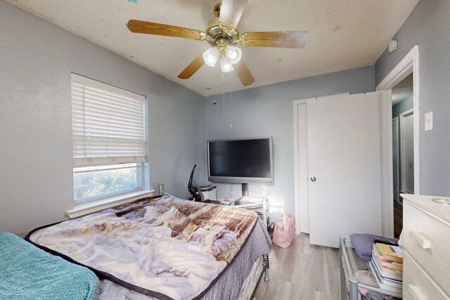 bedroom featuring ceiling fan, a textured ceiling, and light wood-type flooring