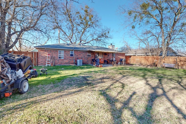 rear view of house with central AC unit and a lawn