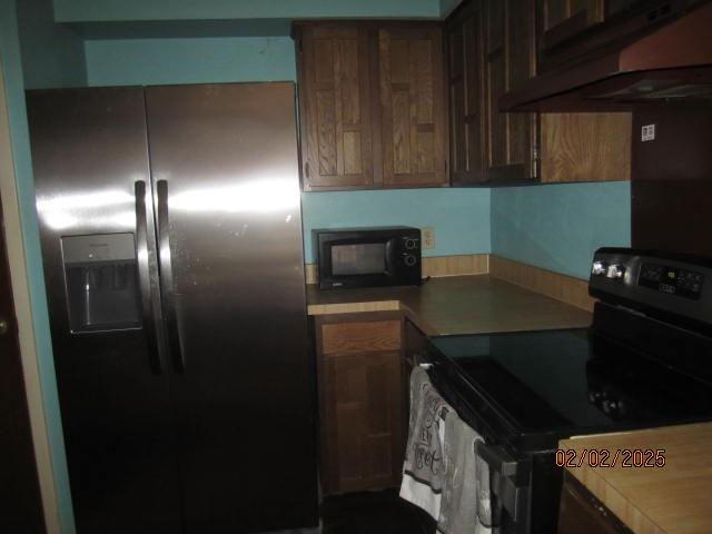 kitchen with electric range and stainless steel refrigerator with ice dispenser