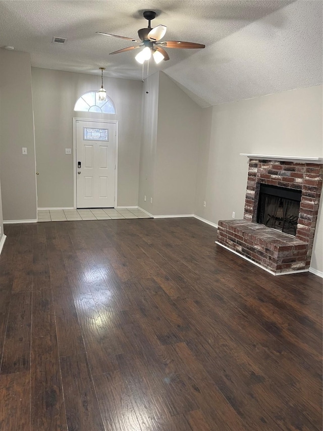 unfurnished living room with hardwood / wood-style floors, a fireplace, lofted ceiling, ceiling fan, and a textured ceiling