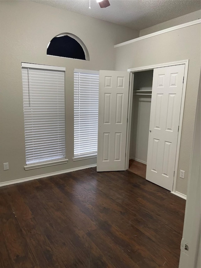 unfurnished bedroom with dark hardwood / wood-style flooring, ceiling fan, a closet, and a textured ceiling