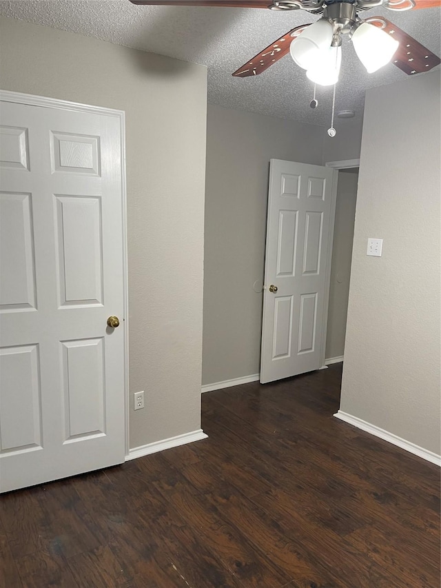 empty room with dark hardwood / wood-style flooring, a textured ceiling, and ceiling fan