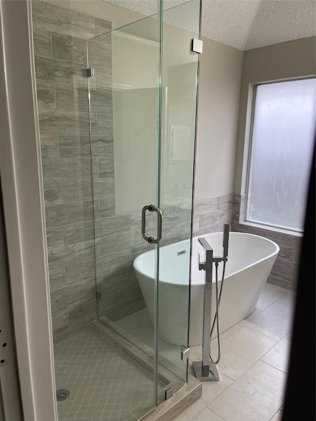 bathroom with tile walls, independent shower and bath, and a textured ceiling