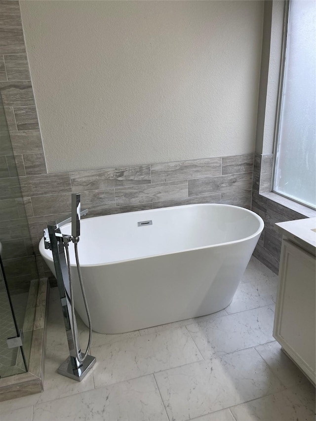 bathroom with tile walls, vanity, and a washtub