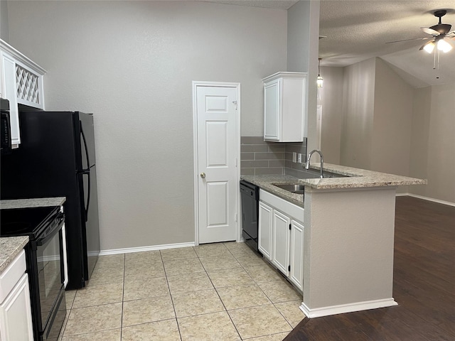 kitchen with sink, kitchen peninsula, white cabinets, light stone countertops, and black appliances