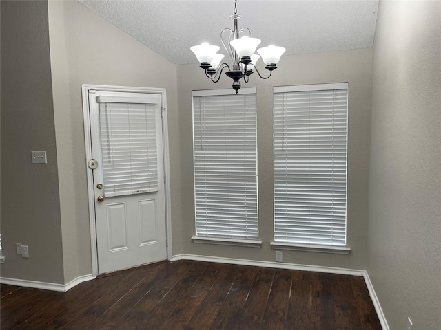 interior space with lofted ceiling, a chandelier, a textured ceiling, and dark hardwood / wood-style flooring