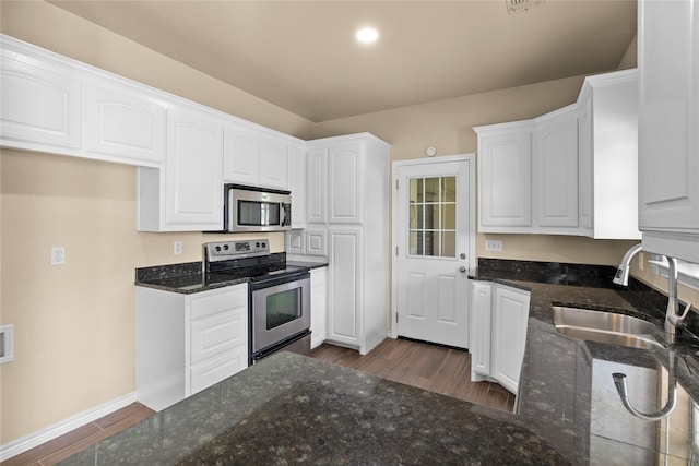 kitchen with stainless steel appliances, sink, white cabinets, and dark stone counters