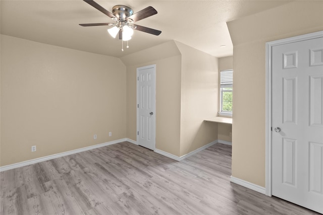 spare room featuring ceiling fan, built in desk, and light hardwood / wood-style floors