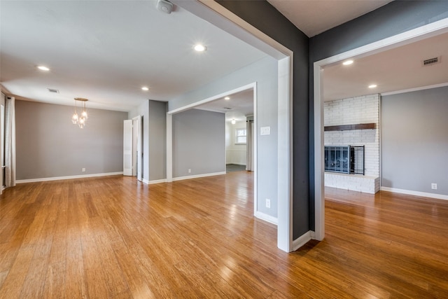 unfurnished living room featuring light hardwood / wood-style flooring, a fireplace, and an inviting chandelier