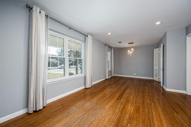 empty room with a notable chandelier and wood-type flooring