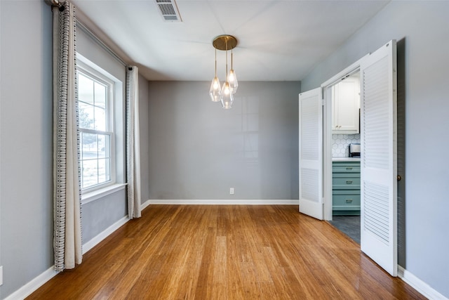 unfurnished dining area featuring an inviting chandelier and light hardwood / wood-style flooring