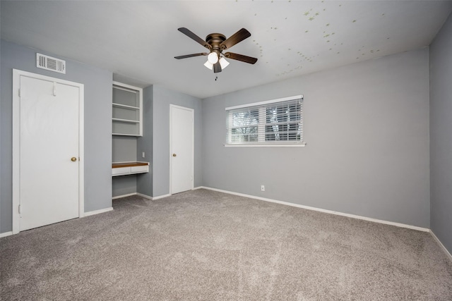 unfurnished bedroom featuring ceiling fan, built in desk, and carpet