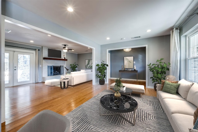 living room with a brick fireplace, french doors, and light wood-type flooring