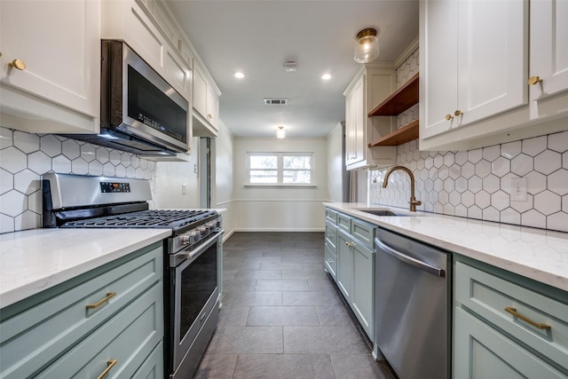 kitchen featuring sink, stainless steel appliances, light stone counters, dark tile patterned flooring, and decorative backsplash