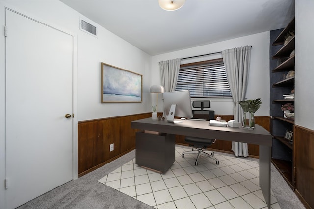 home office with light carpet and wood walls